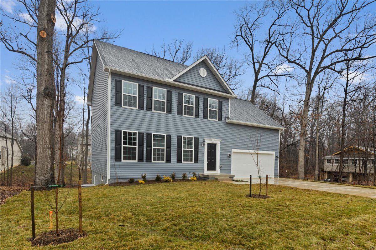 A large house with a garage and a large lawn in front of it.