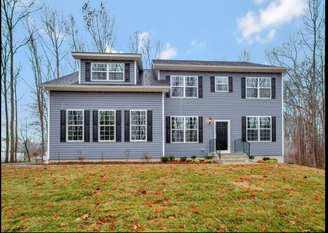 A large house with a lot of windows is sitting on top of a lush green field.