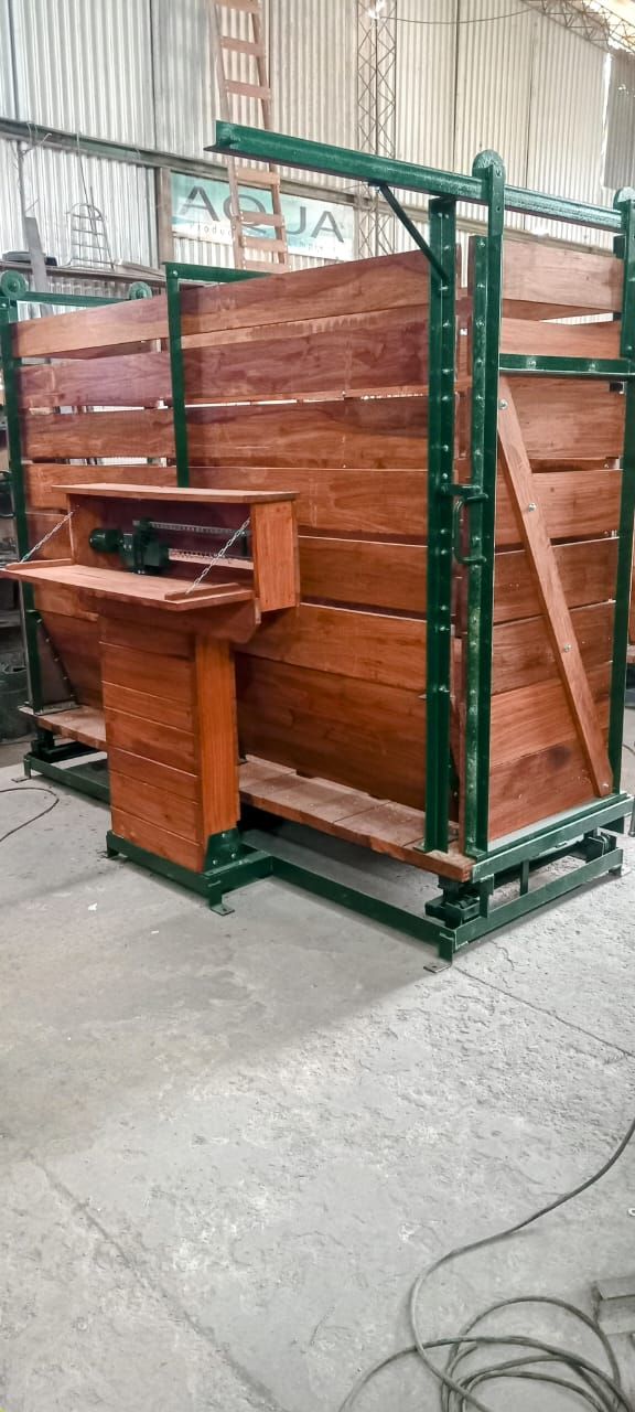 Conducto de madera para ganado con estructura de metal verde en un taller.