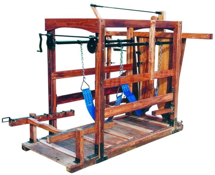 Dispositivo de madera con ataduras y sistema de poleas, probablemente utilizado para sujetar o castigar a personas.