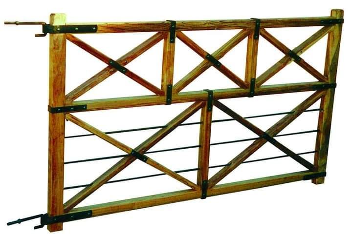 Puerta de granja de madera con forma de X, bisagras de metal negro y alambre horizontal.