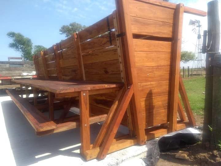 Mesa de picnic de madera con respaldo en un día soleado.