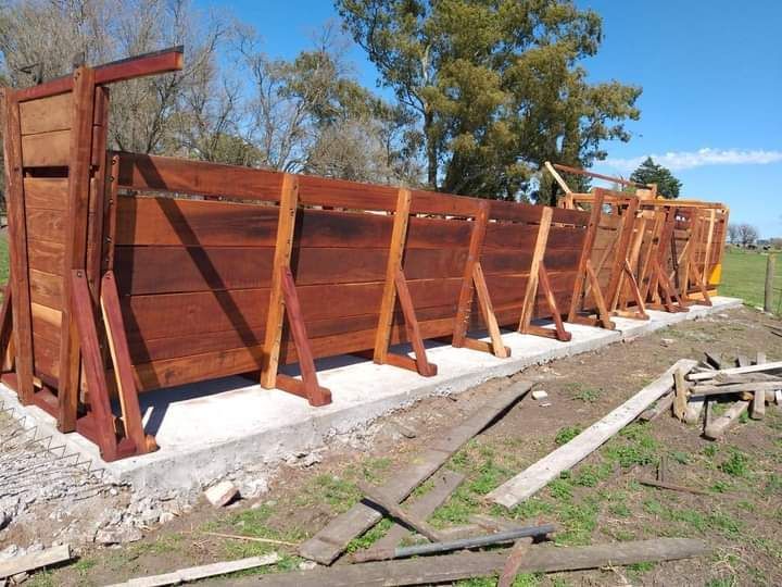 Valla de madera en construcción sobre una base de hormigón; situada en un campo de hierba.