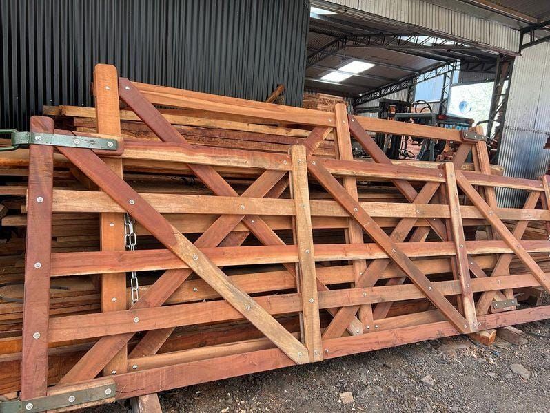 Pila de puertas de granja de madera, de color marrón rojizo, con refuerzos diagonales y herrajes metálicos
