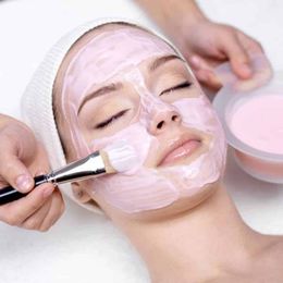 Person getting a facial treatment with gloved hands, eyes closed, white headband.