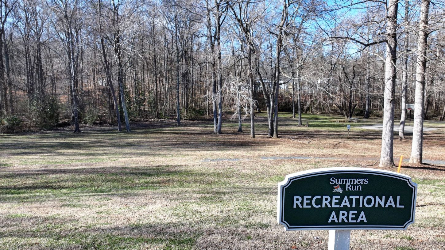 A recreational area sign in a park with trees in the background.