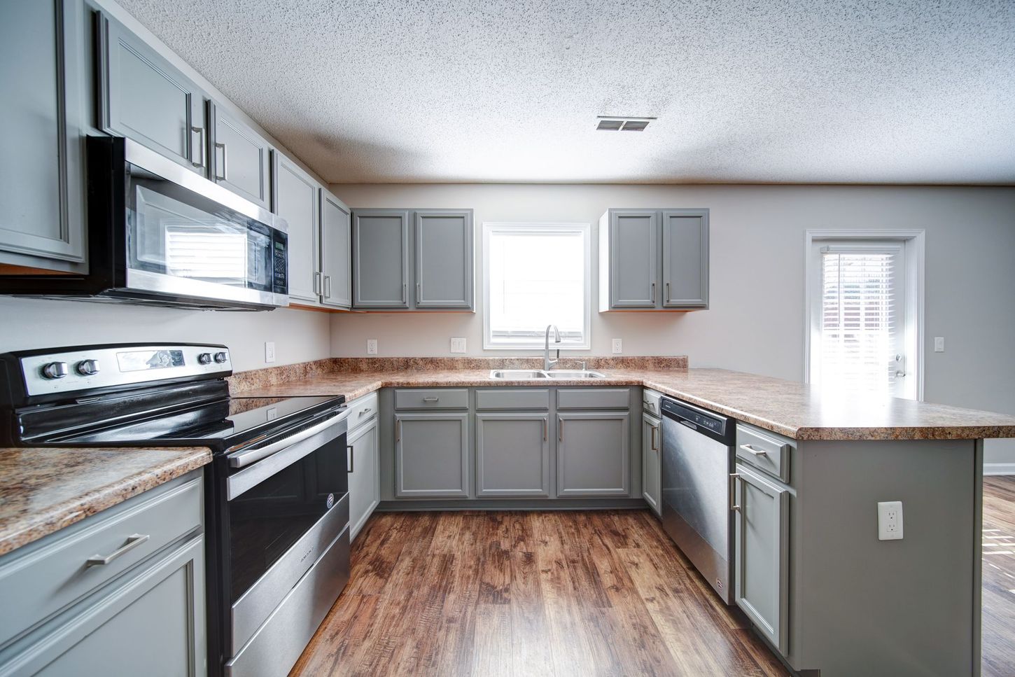 A kitchen with stainless steel appliances and gray cabinets