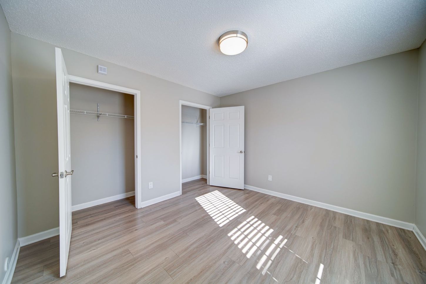 An empty bedroom with hardwood floors and a closet.