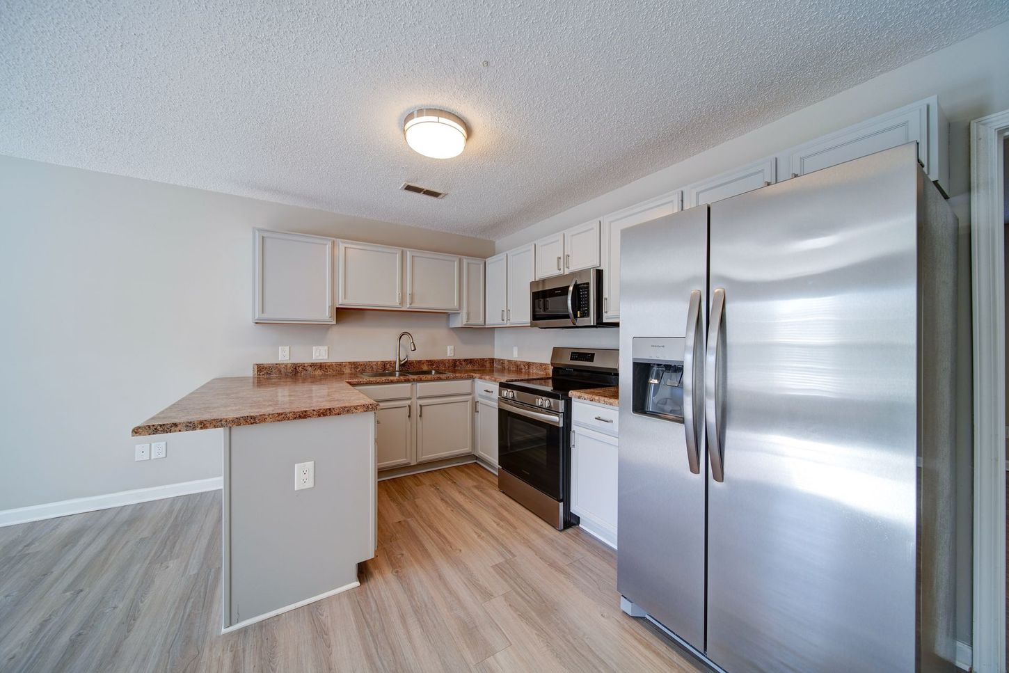 A kitchen with a stainless steel refrigerator , stove , microwave and sink.