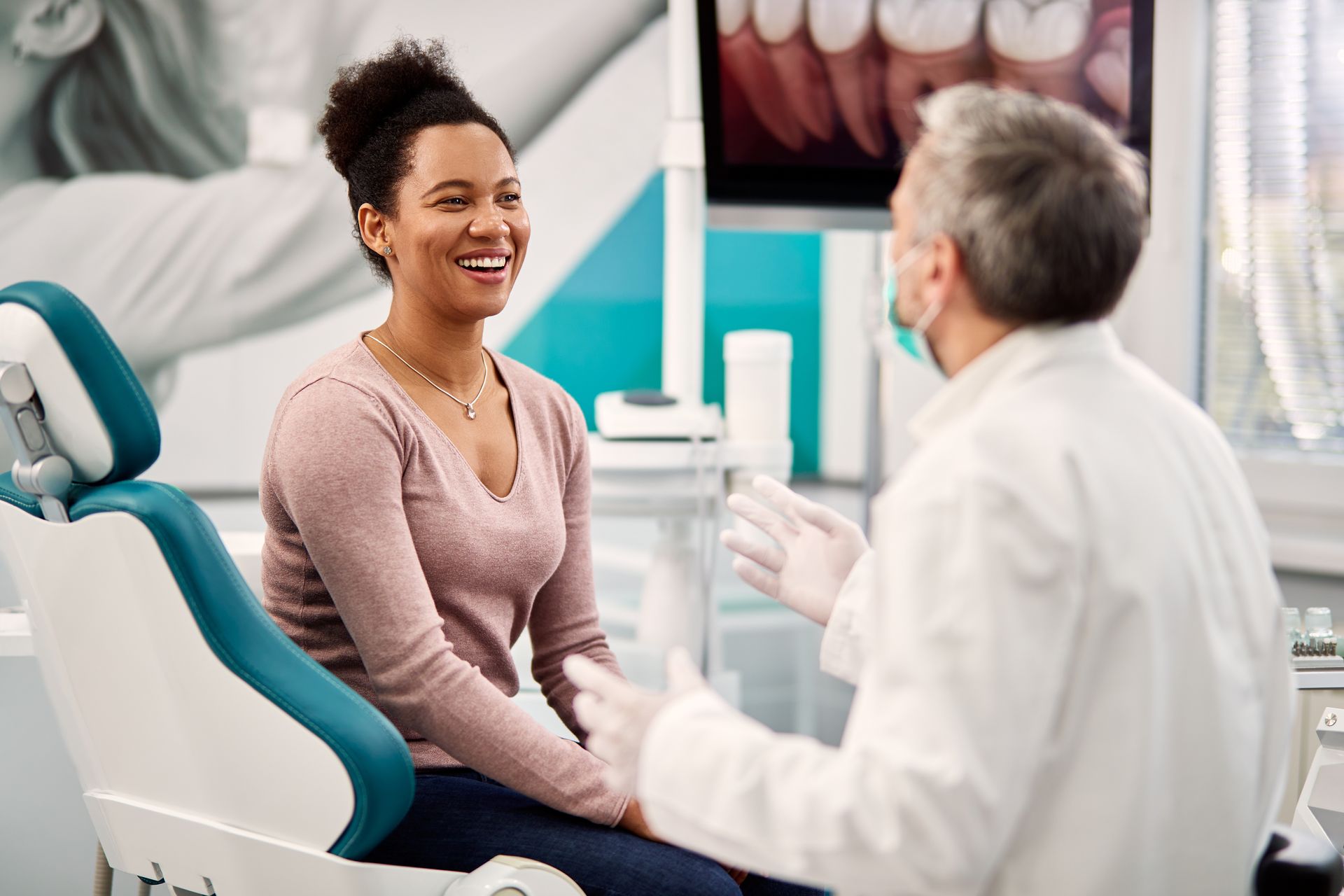 Custom Dentures — Old Woman Happy With New Dentures in Tukwila, WA A smiling woman talking to her dentist during an appointment at the dental clinic.
