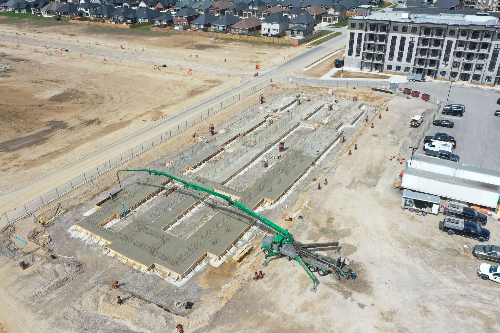 An aerial view of a construction site with a green concrete pump.