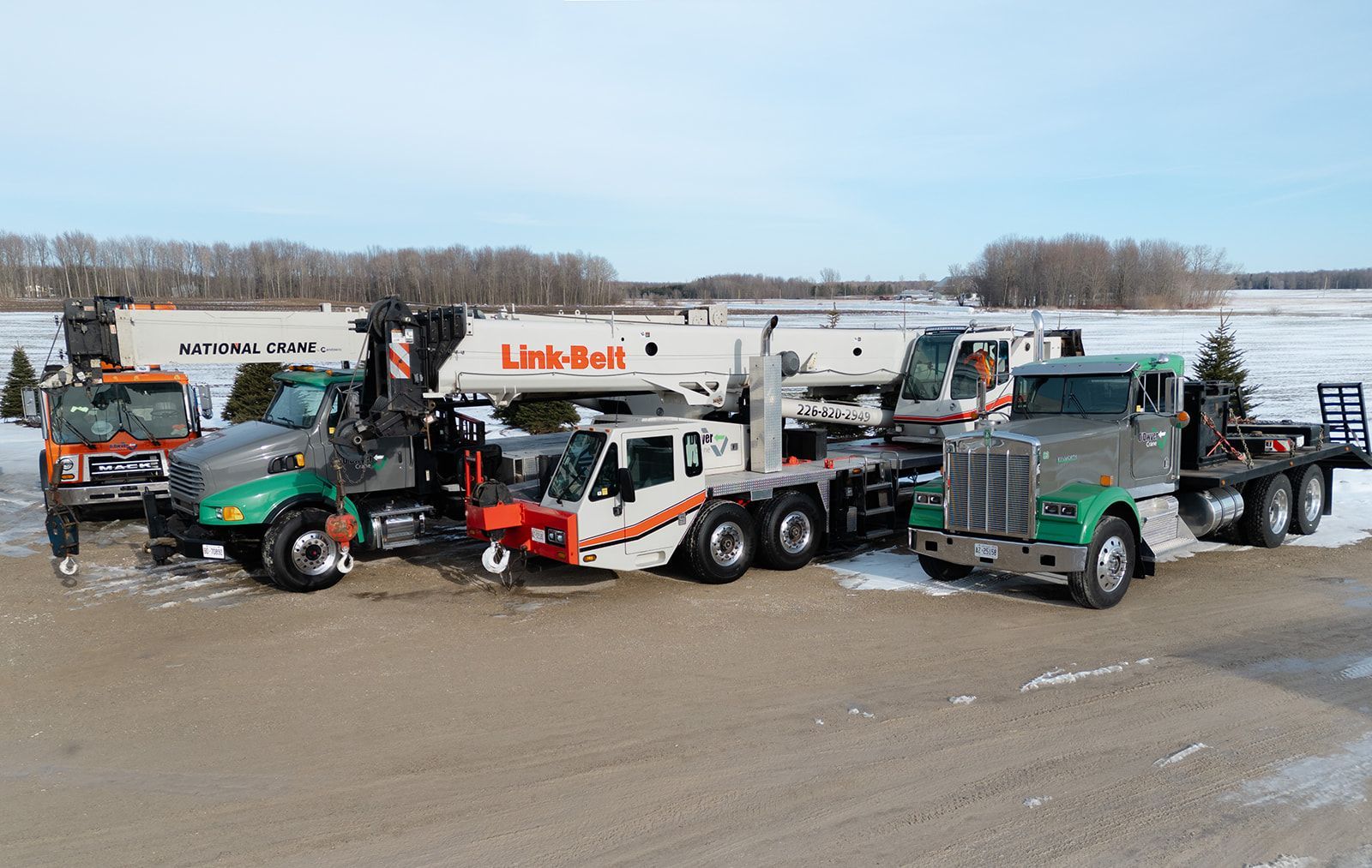A group of trucks are parked next to each other on a snowy road.