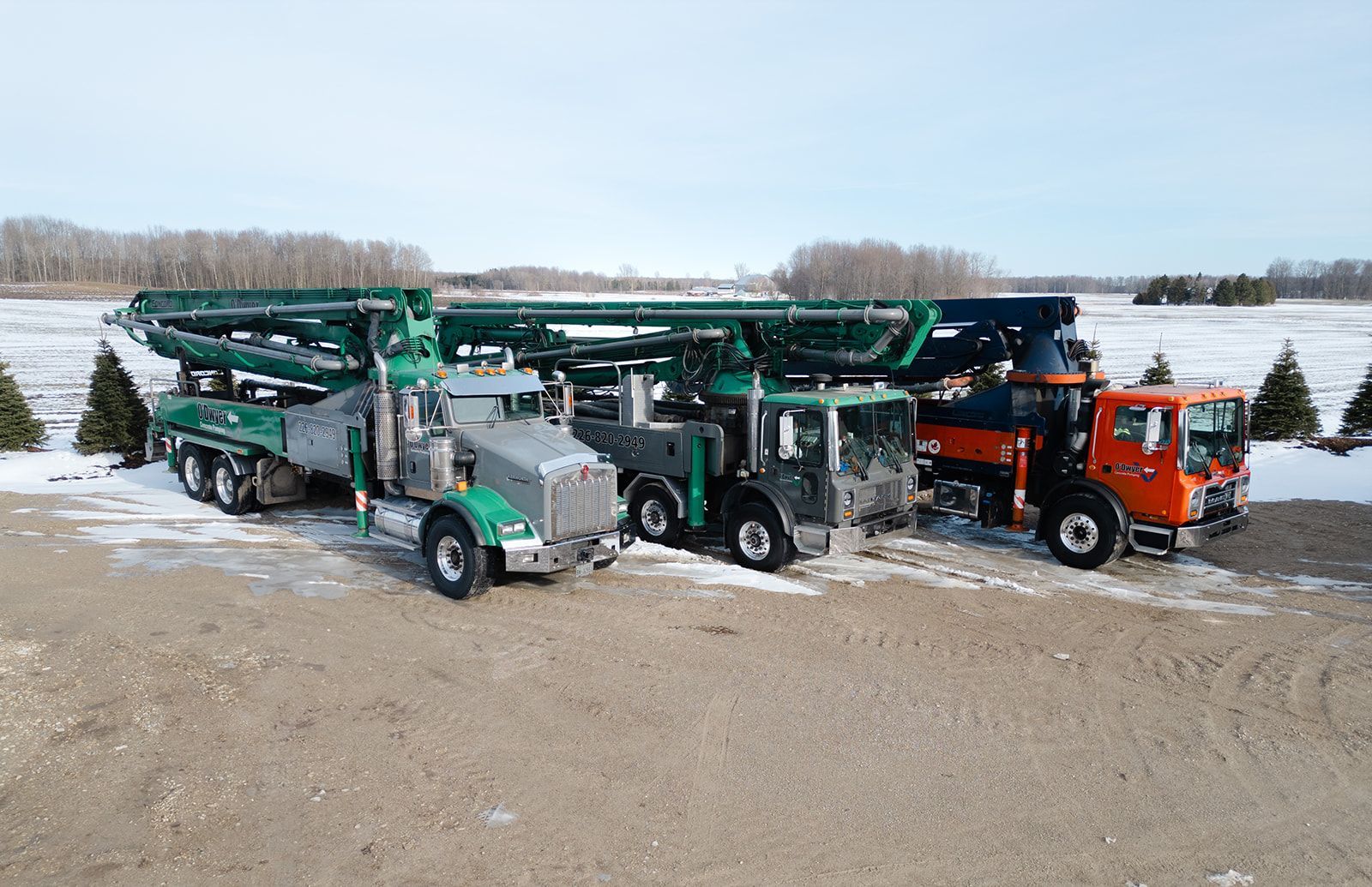 Three trucks are parked next to each other in a snowy field.
