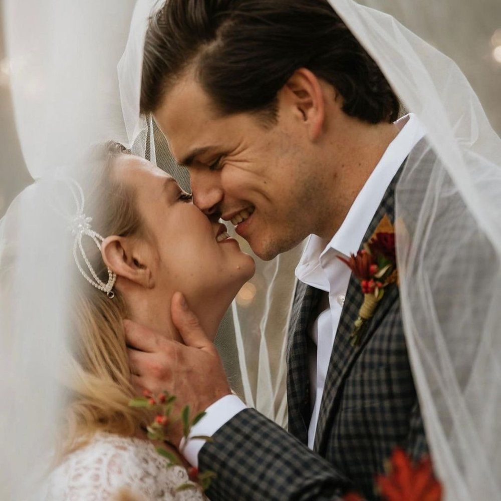 A bride and groom kissing under a veil on their wedding day