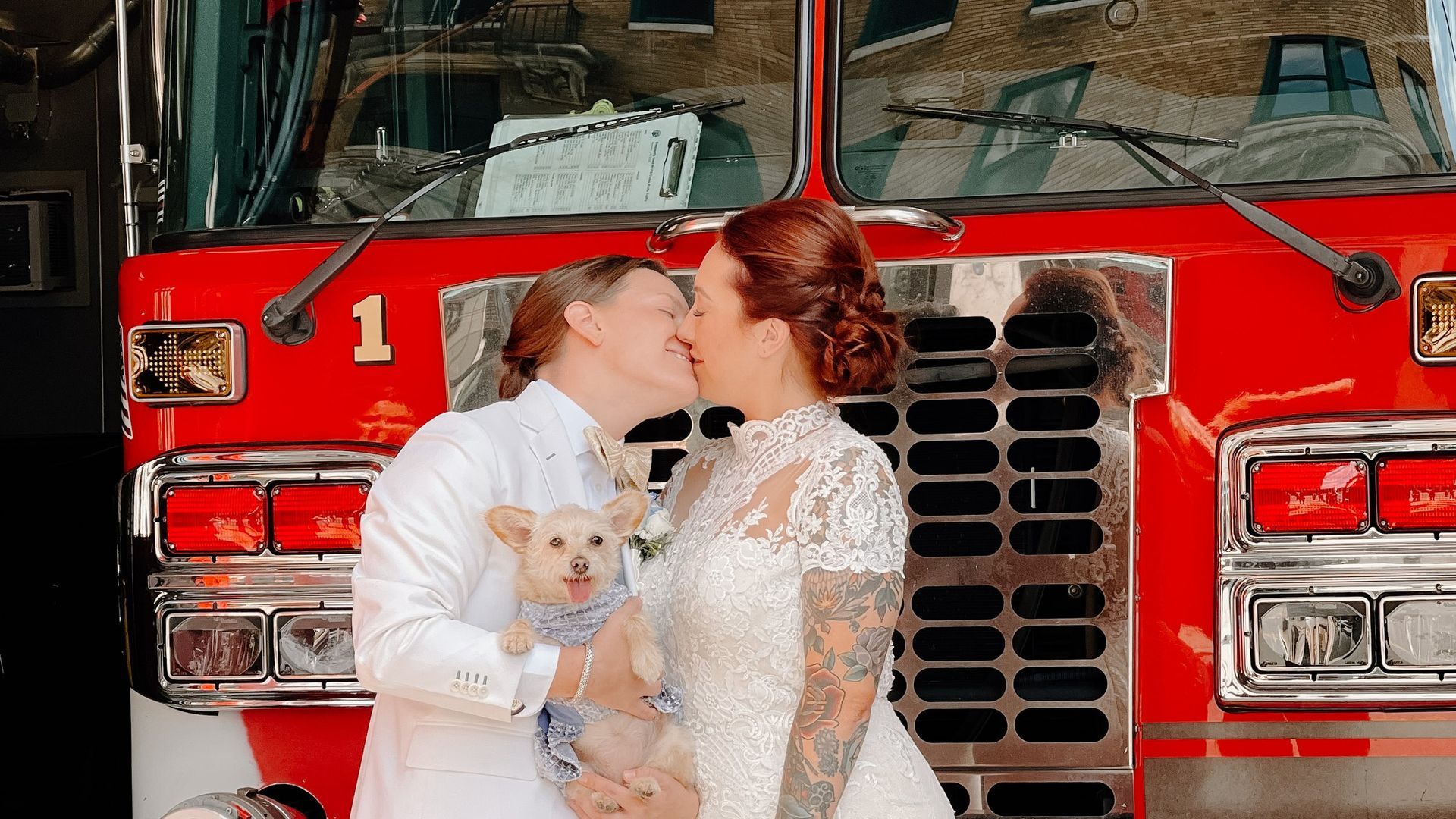 A bride and groom kissing in front of a fire truck