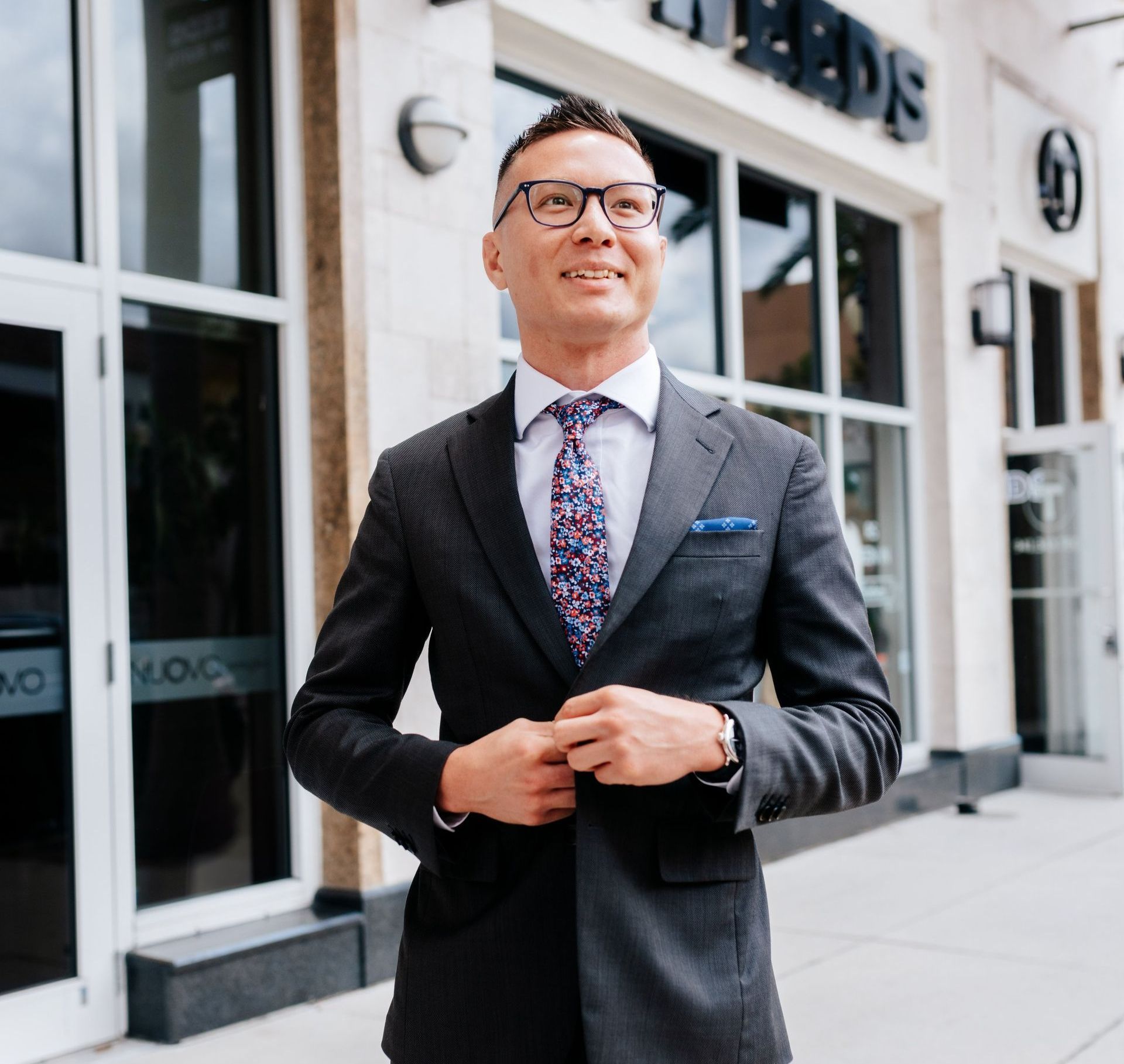 A man in a suit and tie is standing in front of a building.