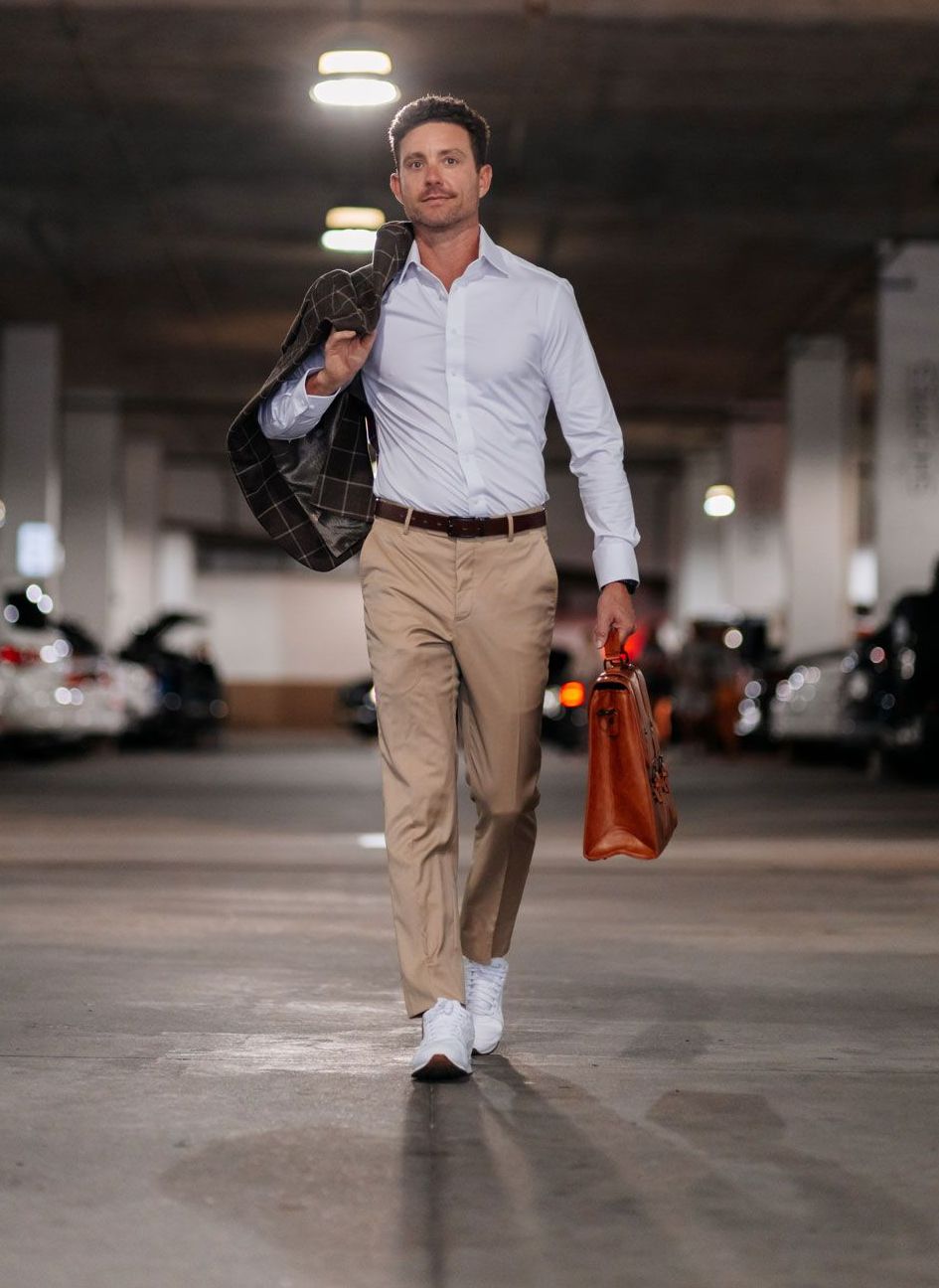 A man is walking through a parking garage holding a briefcase.