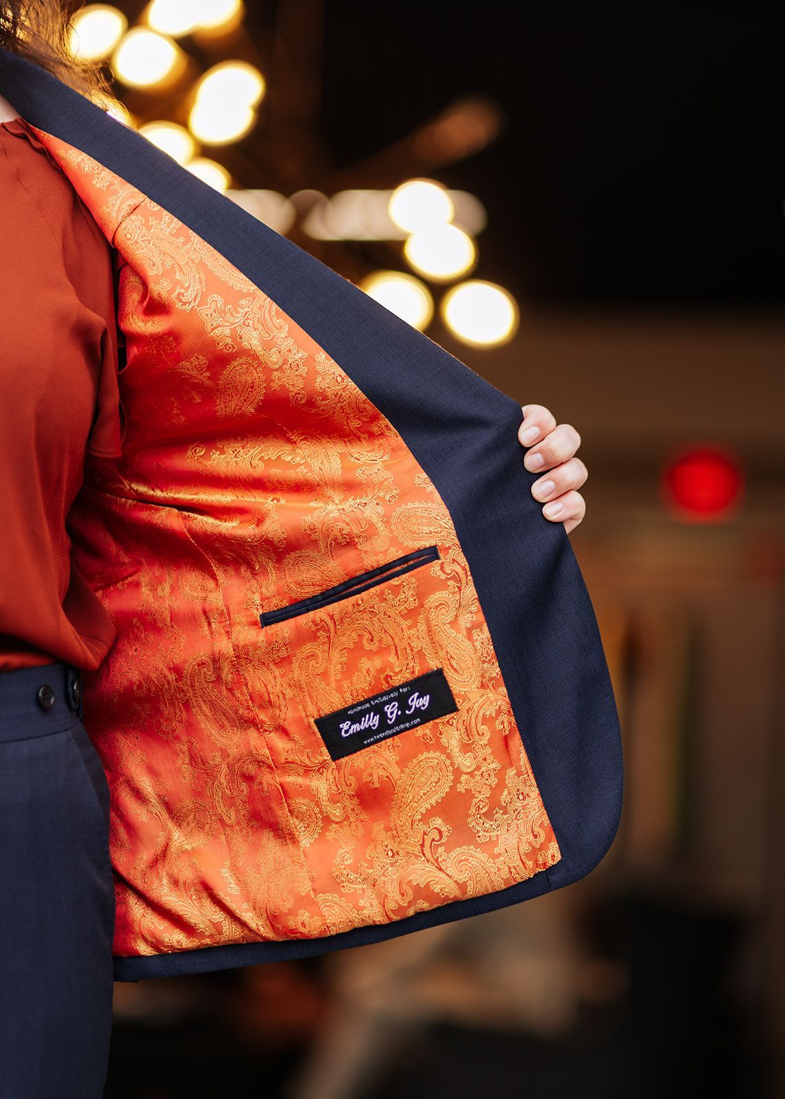 Man in white tuxedo with black lapel and bow tie, opening jacket.