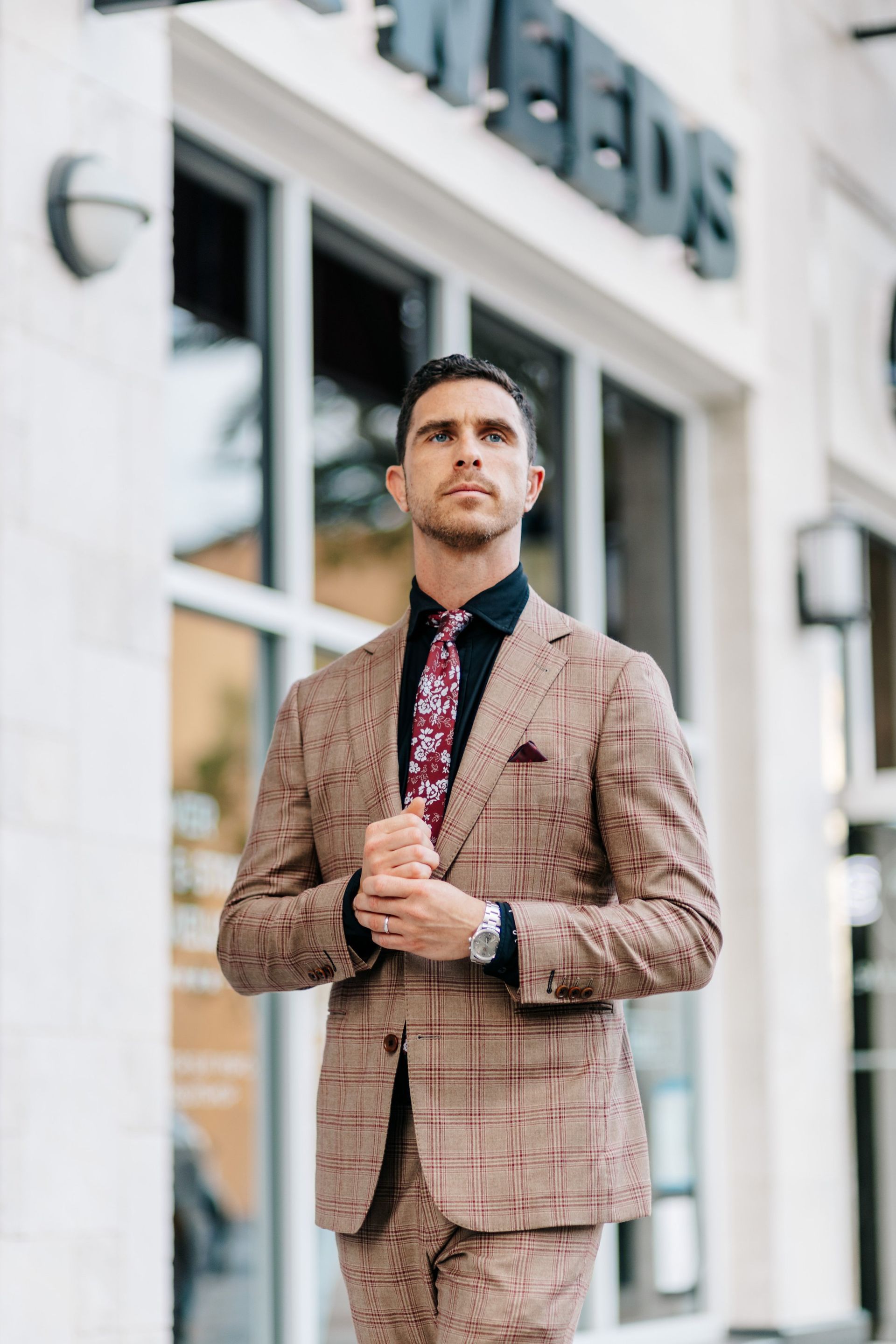 A man in a suit and tie is standing in front of a building.