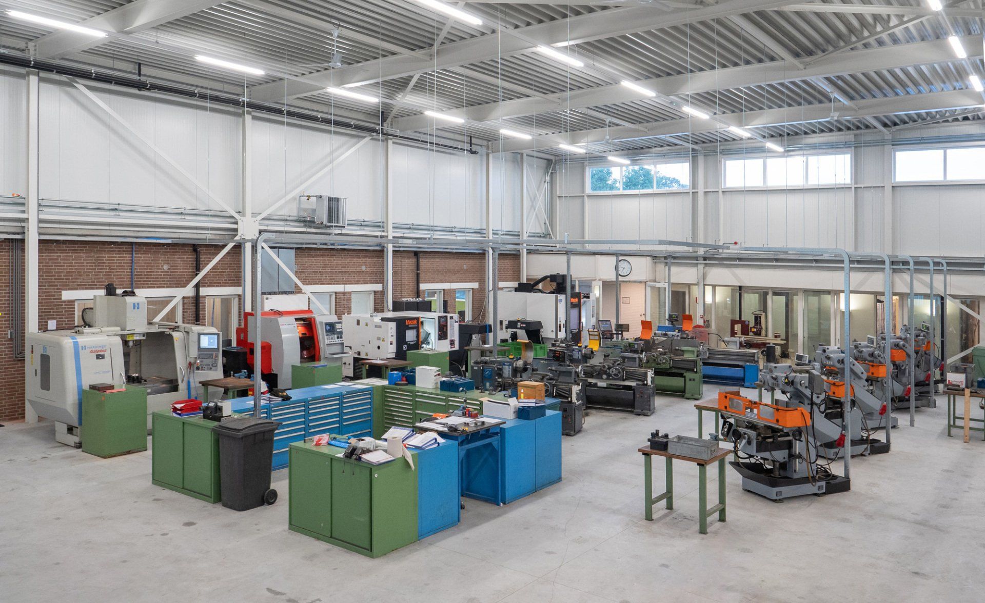 Een groot magazijn vol met machines en tafels.