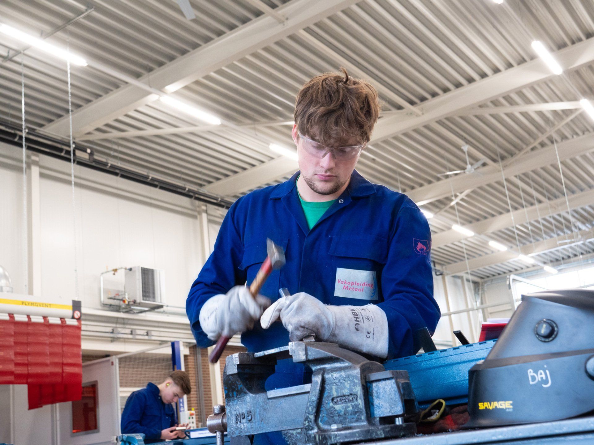 Een man in een blauw uniform werkt aan een machine in een fabriek.