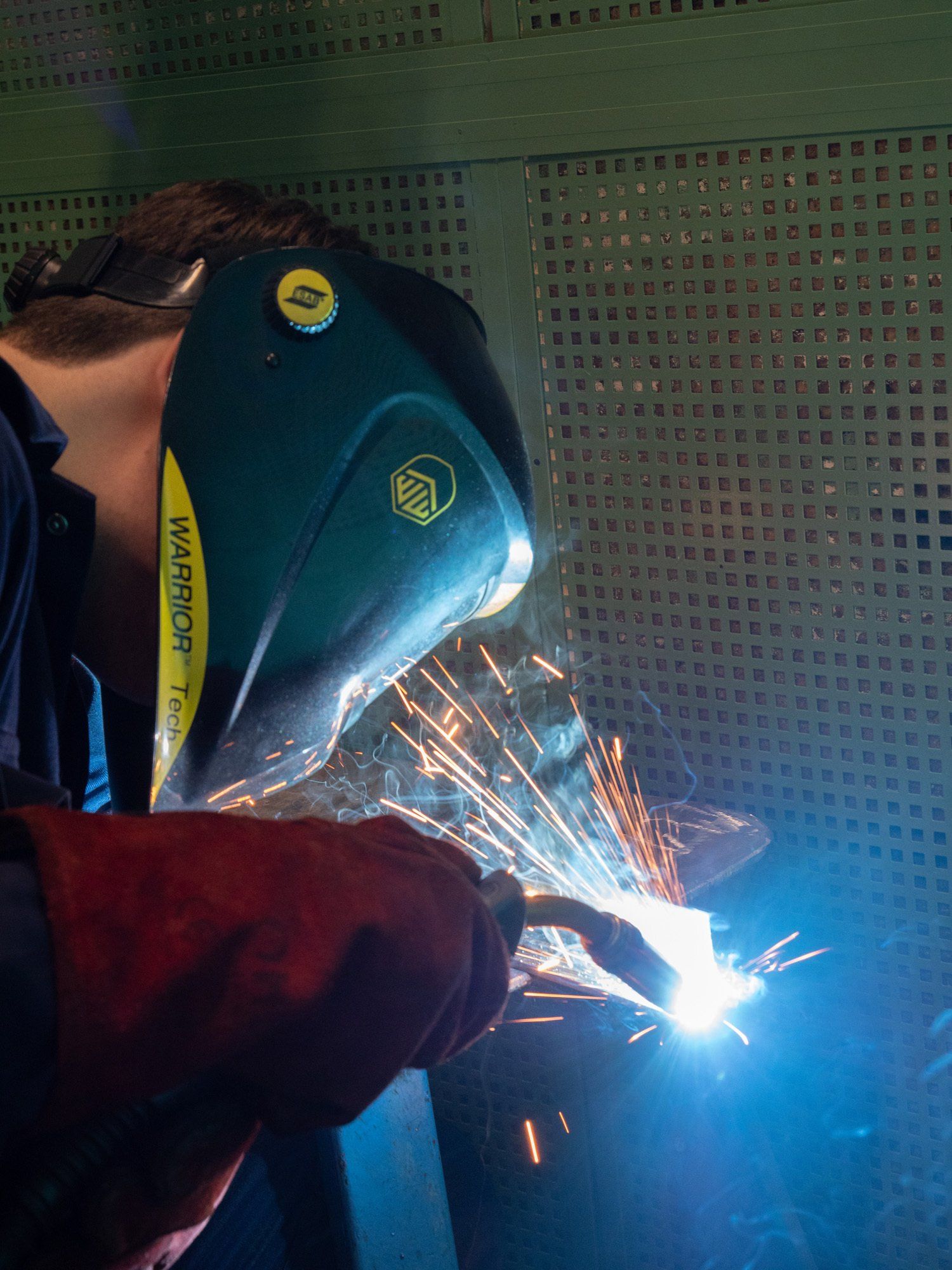 Een man met een lasmasker last een stuk metaal.