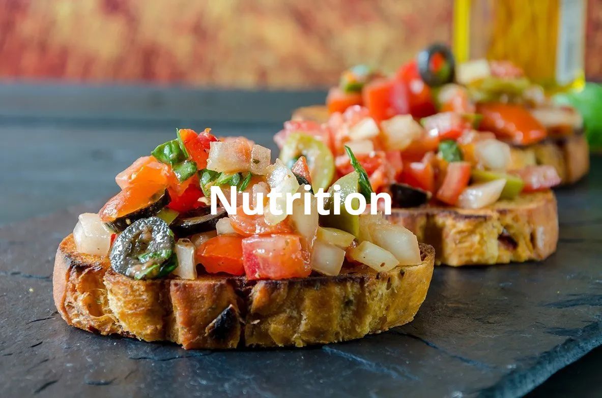 Bruschetta topped with diced tomatoes, onions, olives, and herbs on a slate surface. 