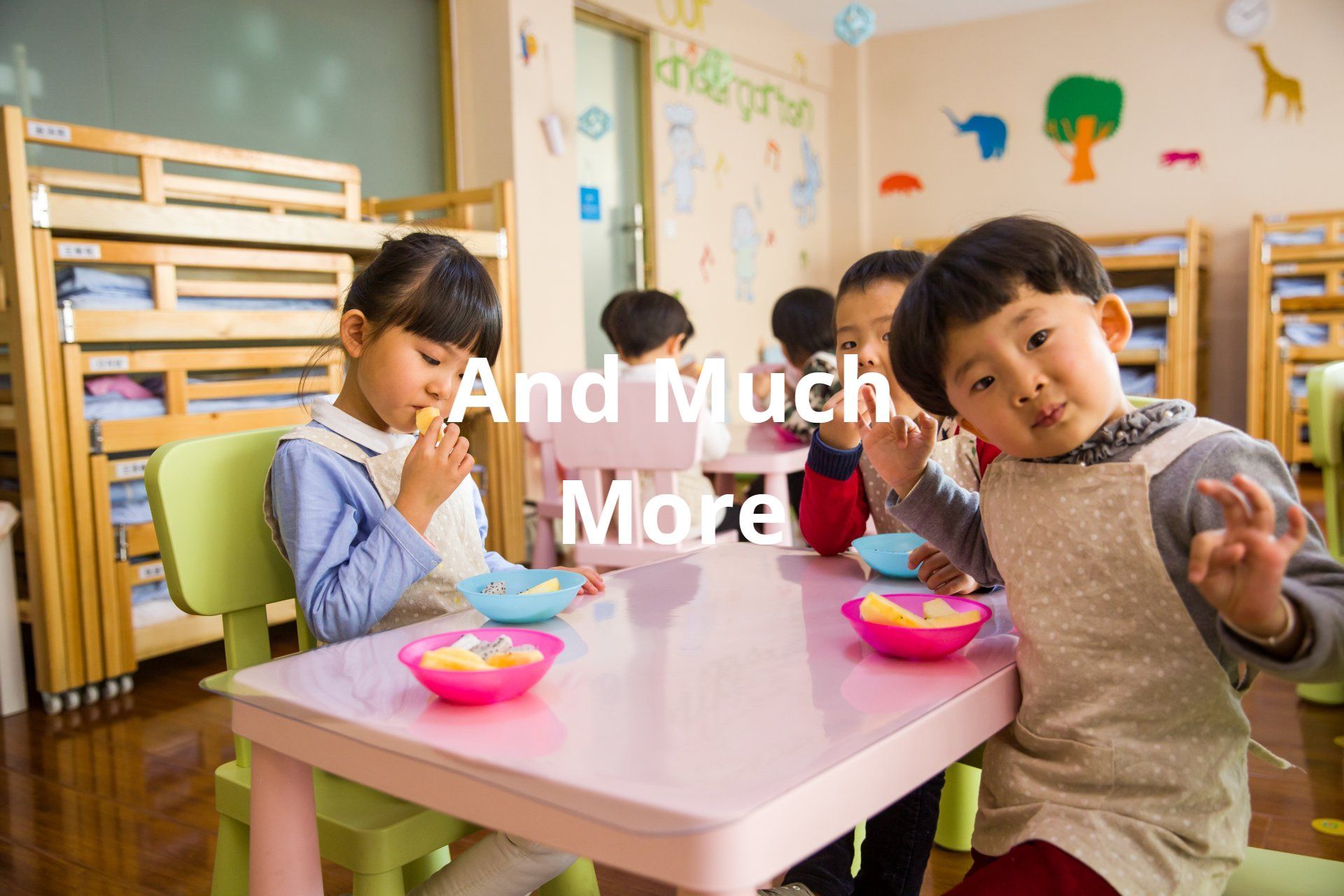 Children at a table in a classroom eat fruit. One child looks at the camera.