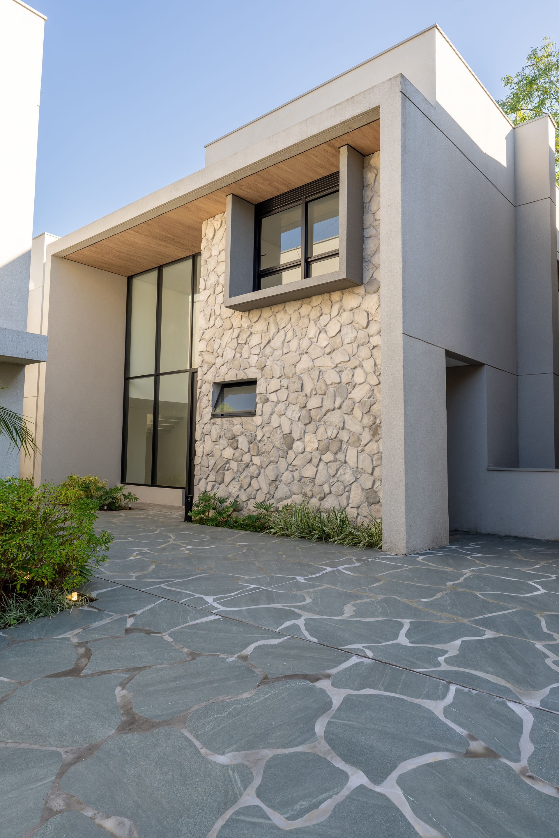 Uma casa moderna com parede de pedra e entrada de automóveis