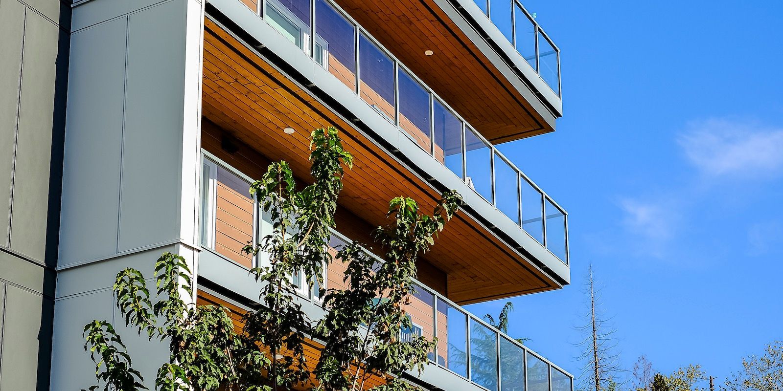 Modern apartment building with wood balconies and blue sky.