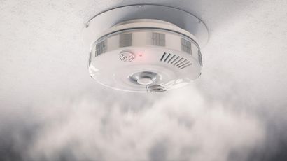 Un détecteur de fumée est suspendu au plafond et de la fumée en sort.