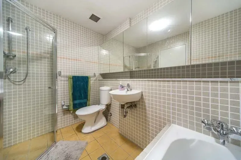 Bathroom with shower, toilet, sink, and tub. White tiled walls with teal and gray accents.