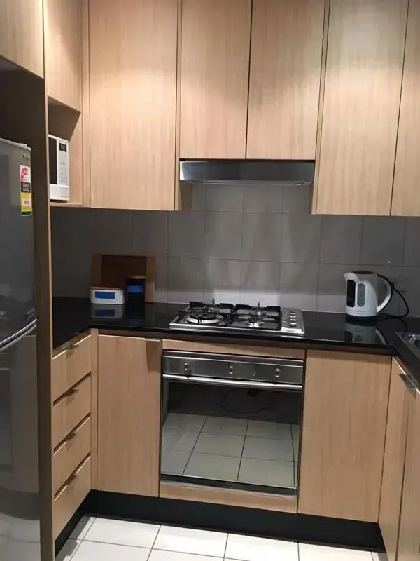 Small kitchen with light wood cabinets, stainless steel appliances, and dark countertops.