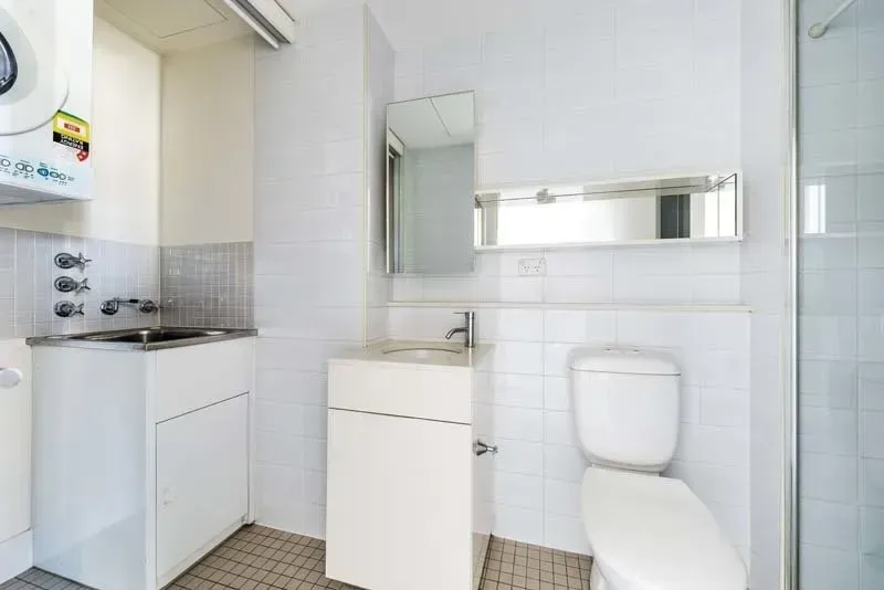 Small white bathroom with a sink, toilet, and washing machine.