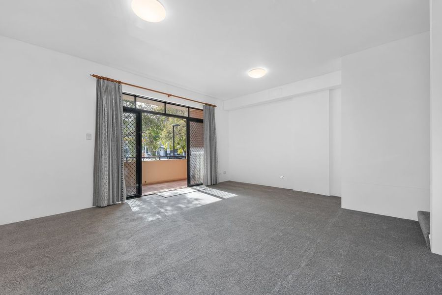 Empty room with gray carpet, white walls, and balcony access through glass doors.