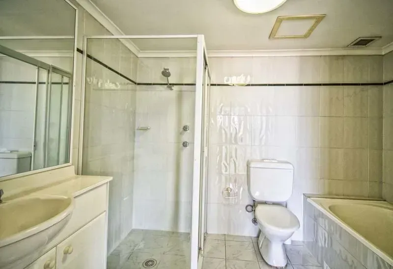 Bathroom with a white toilet, shower, sink, and bathtub. Beige tile walls and floor.