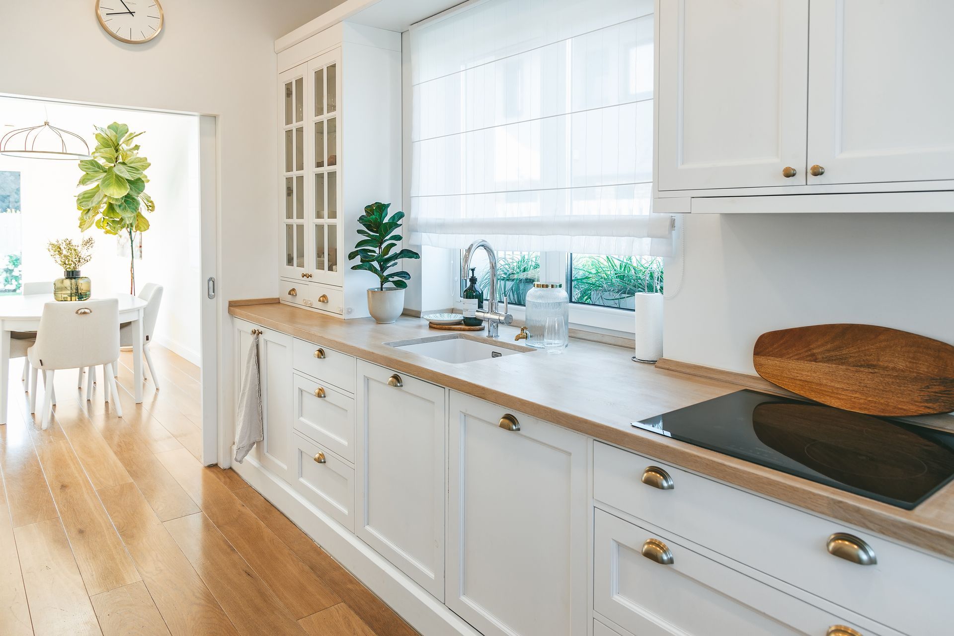 White kitchen with wooden countertops, built-in stove, and open doorway to dining area.