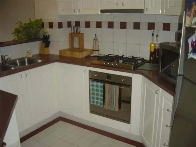 U-shaped kitchen with white cabinets, brown countertops, gas stove, and stainless steel oven.