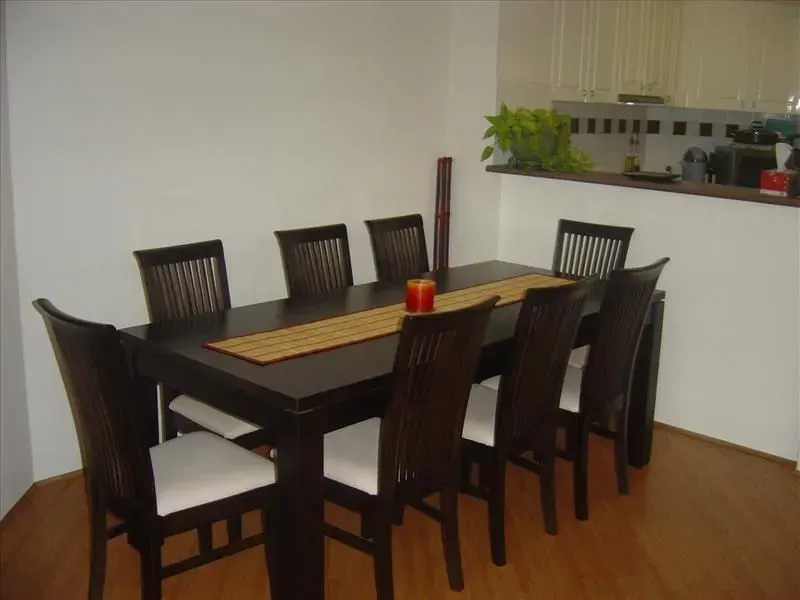 Dining room with dark wood table and chairs, white cushions, and a small decorative runner.