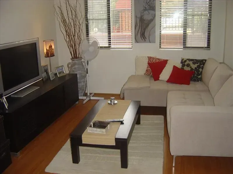 Living room with a sectional sofa, TV, coffee table, and window with blinds.