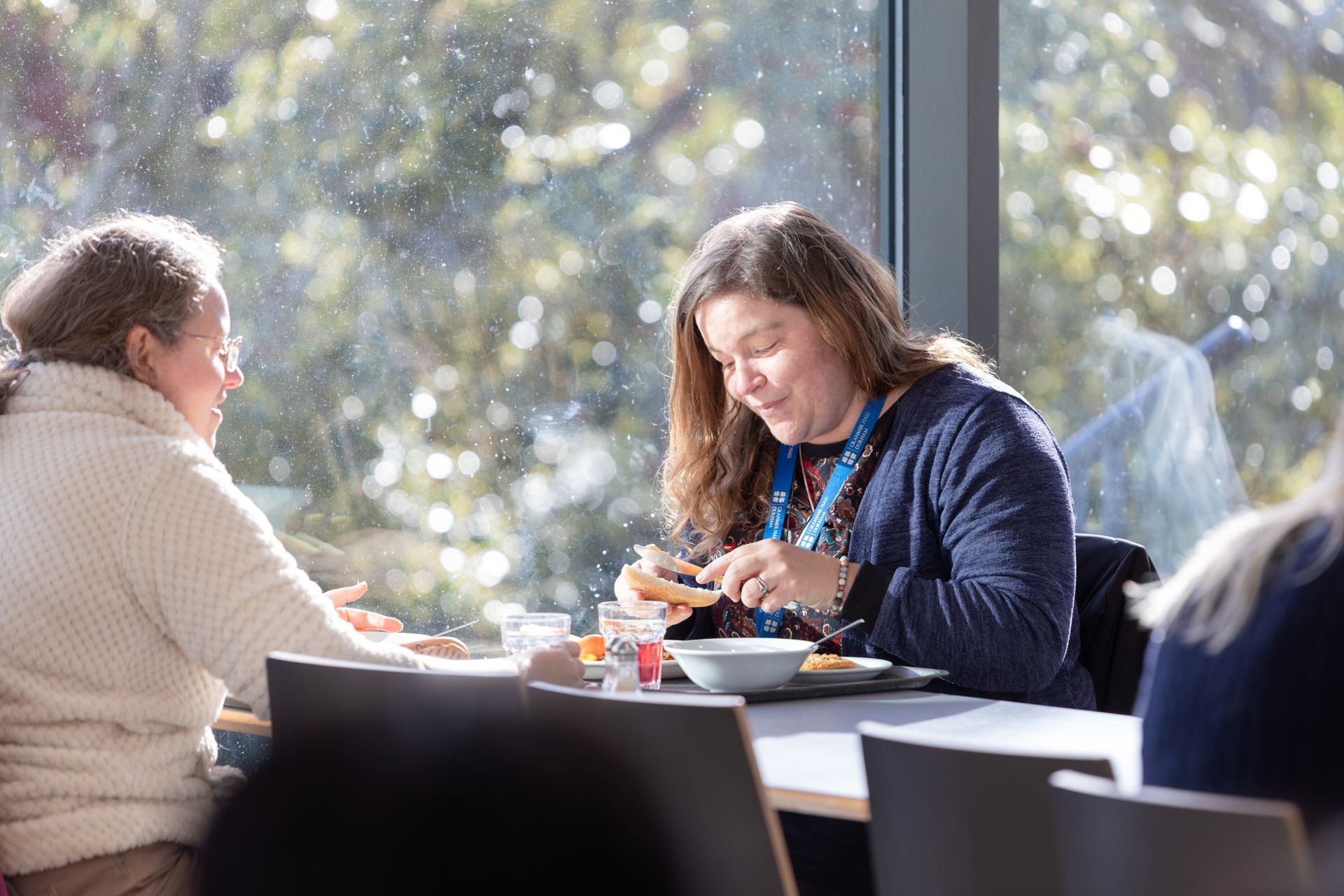 Two people eating at a table by a large window in a bright café