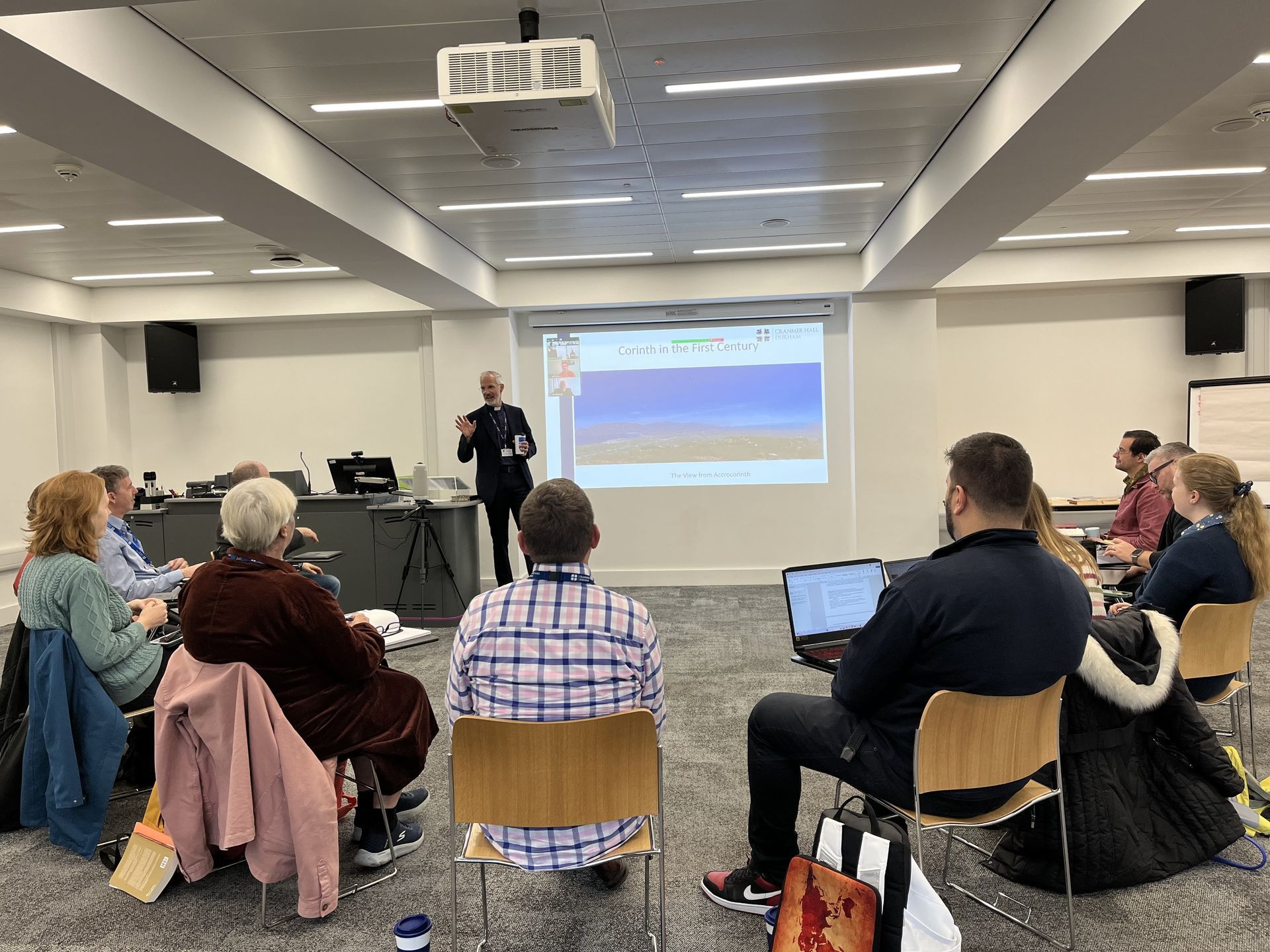 Audience seated in a meeting room watching a presentation on a projected screen