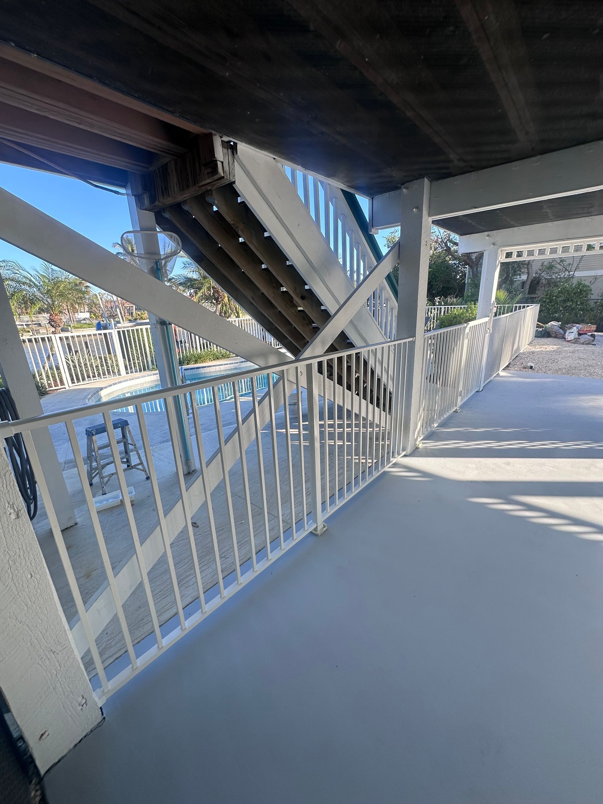 White staircase leading up to a covered deck; railings on both sides; light gray floor.