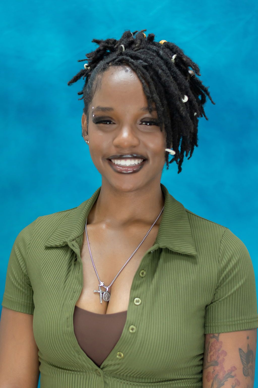 A woman is sitting at a desk with a laptop and a vase of flowers.