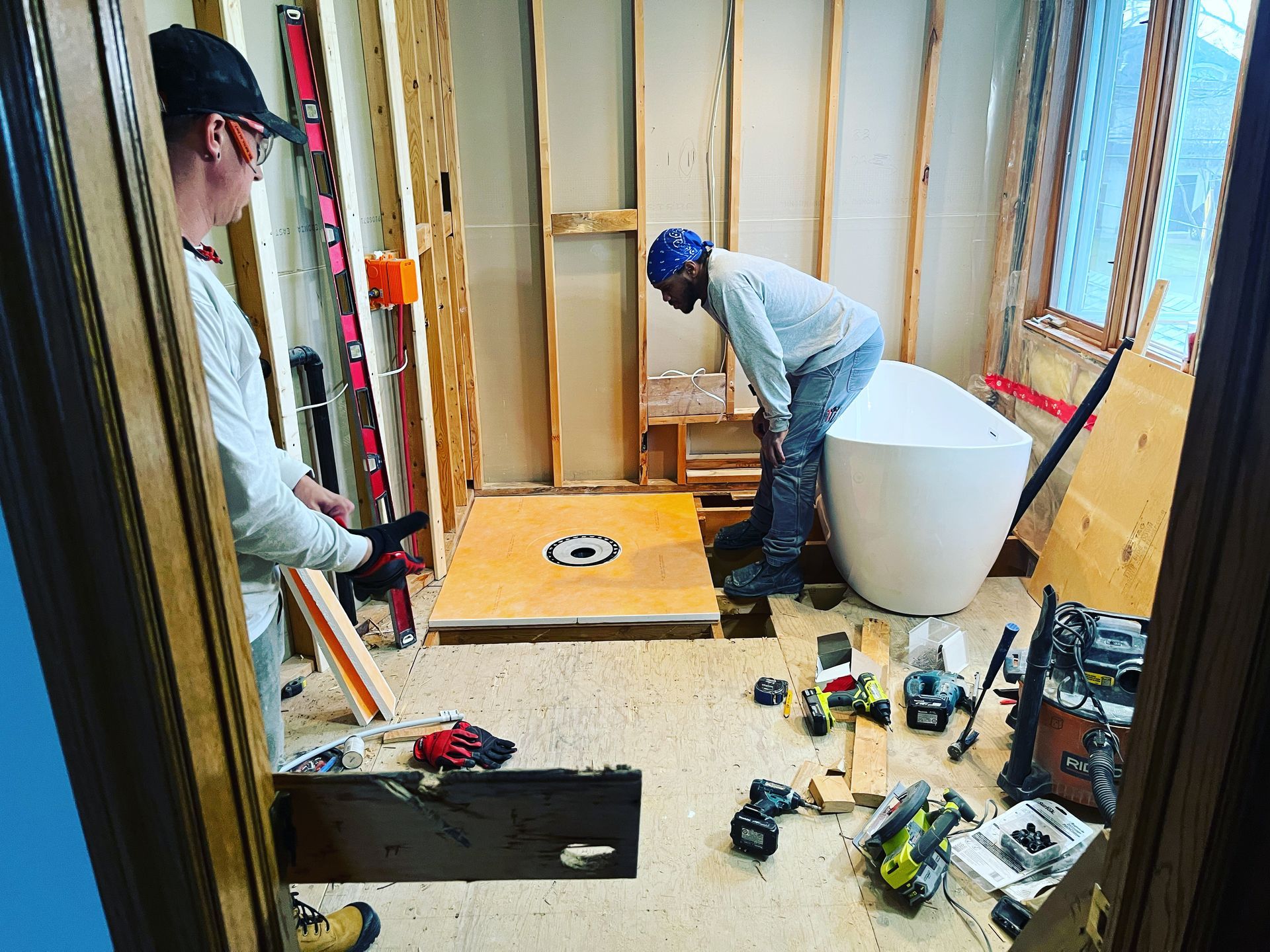 Two men are working in a bathroom under construction.