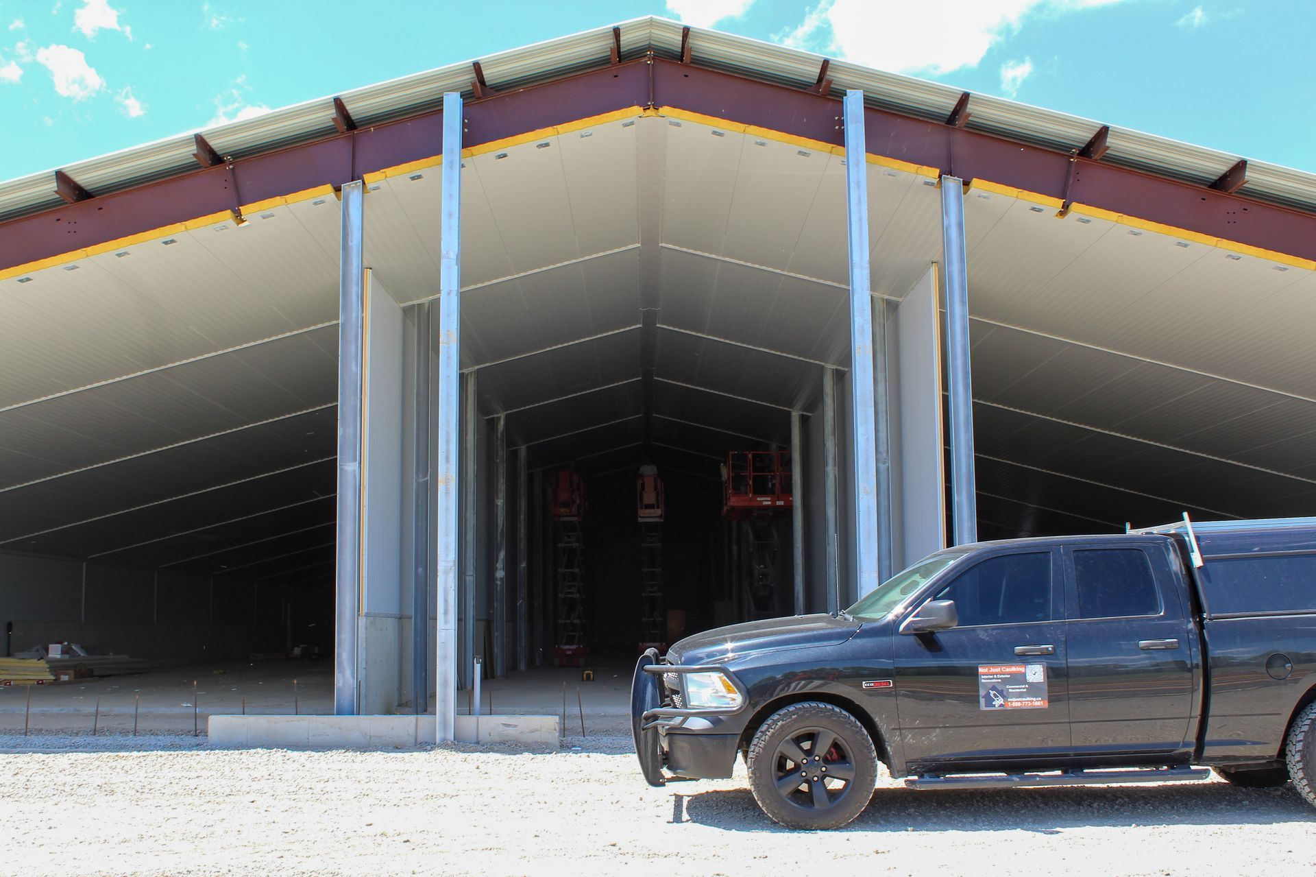 A black truck is parked in front of a building under construction.