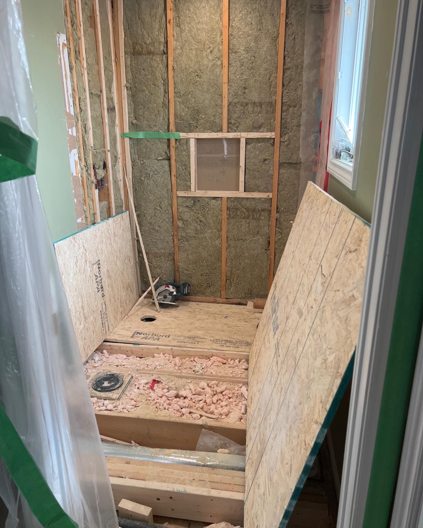 A bathroom under construction with wooden floors and walls.