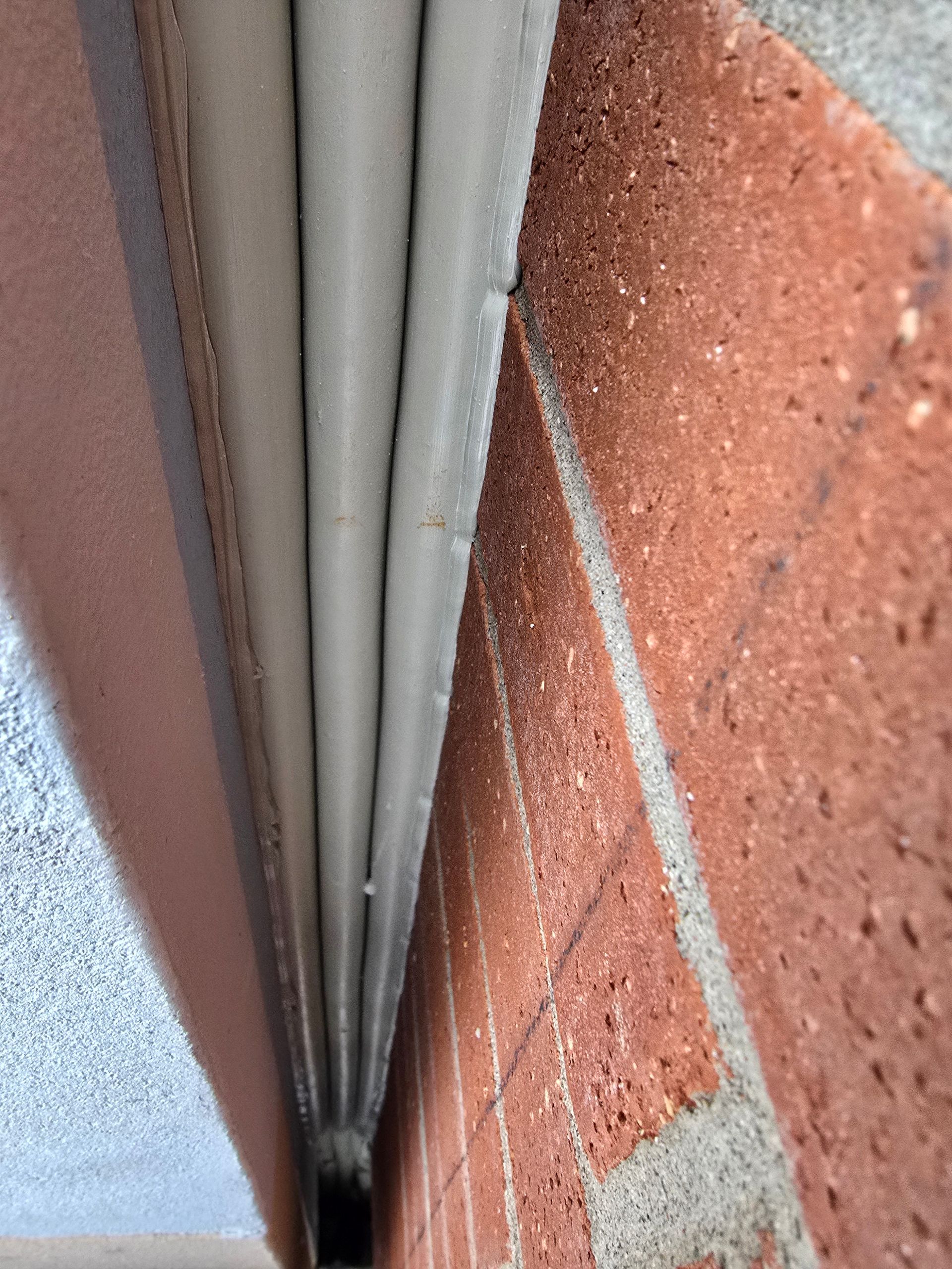 Close-up of a brick wall and grey corrugated material.