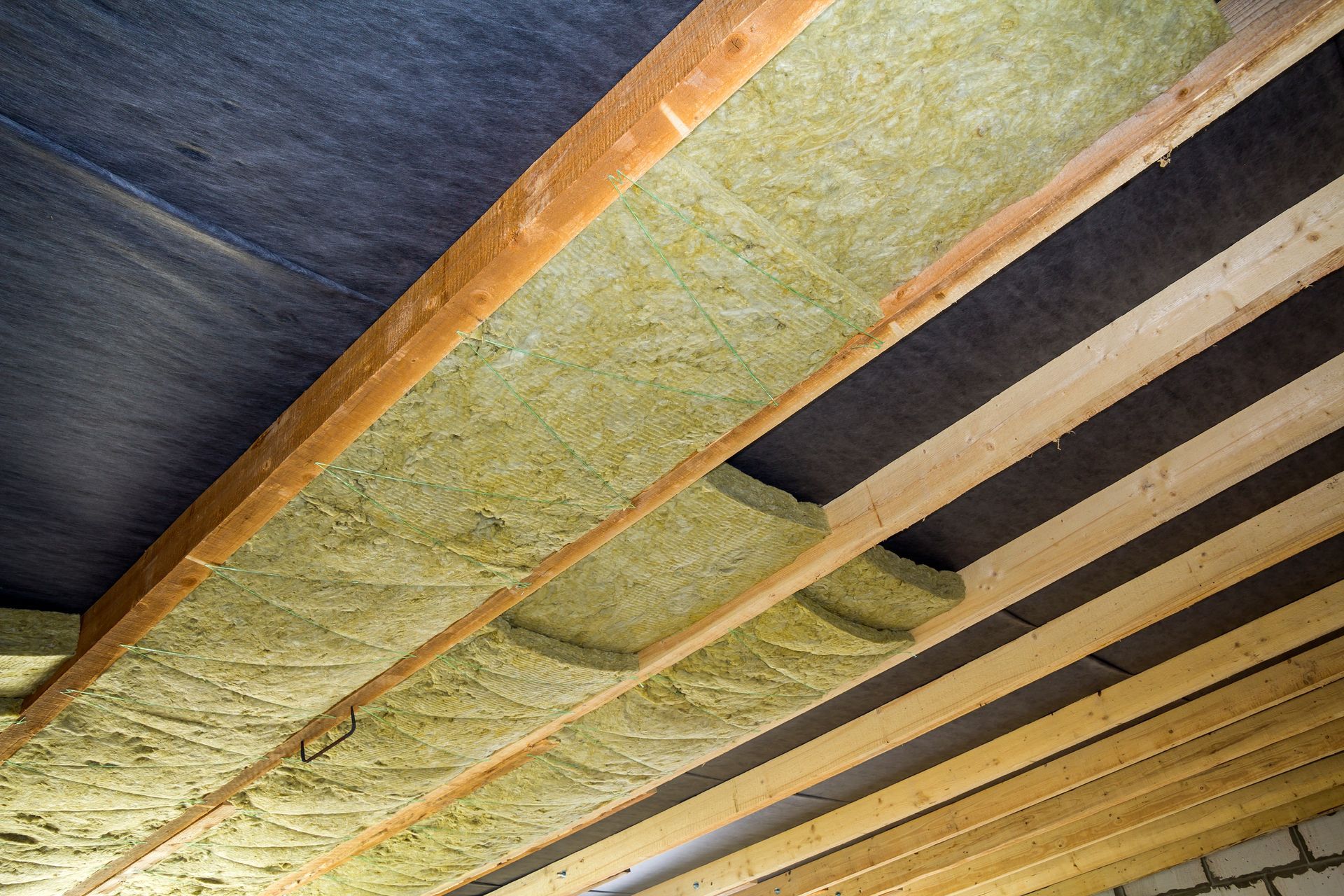 A ceiling with wooden beams and insulation on it.