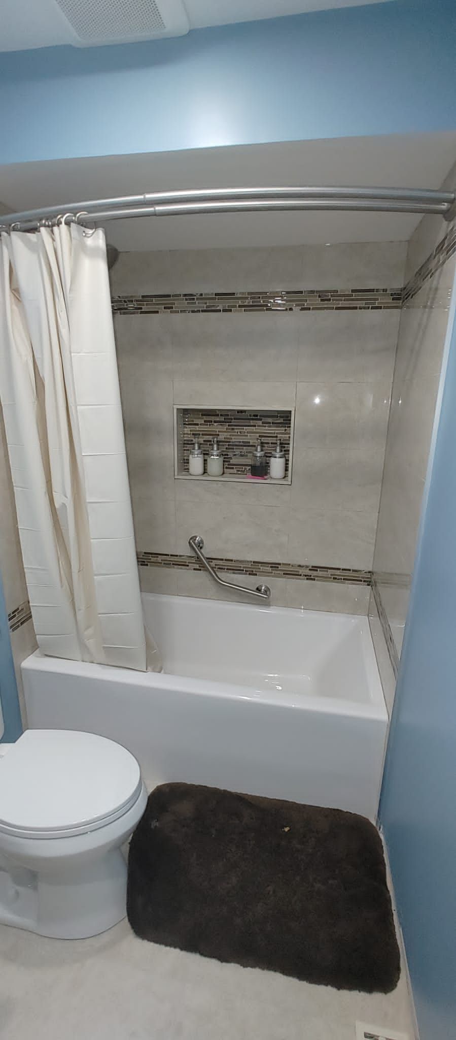 A bathroom with a toilet , bathtub and shower curtain.